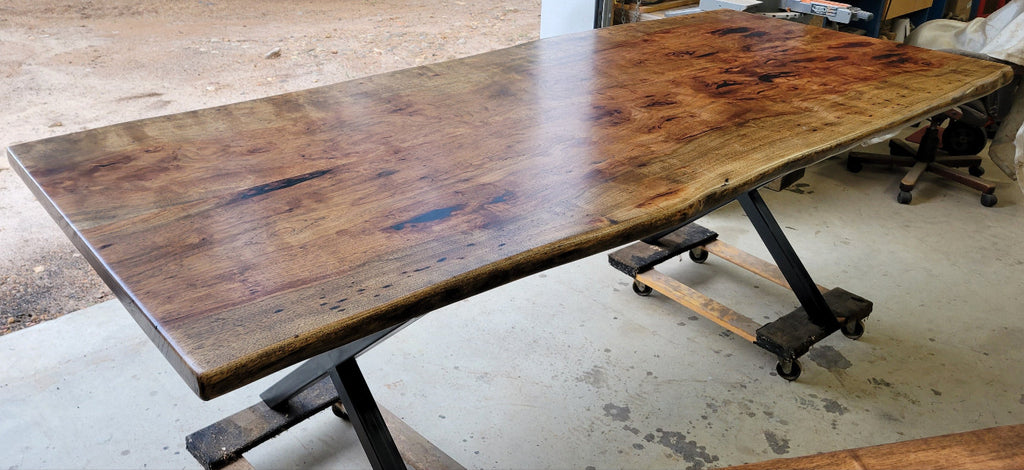 Pecan wood dining table with natural live edge slab top finished in Jacobean stain, handcrafted by Coleto Creek Mill & Design