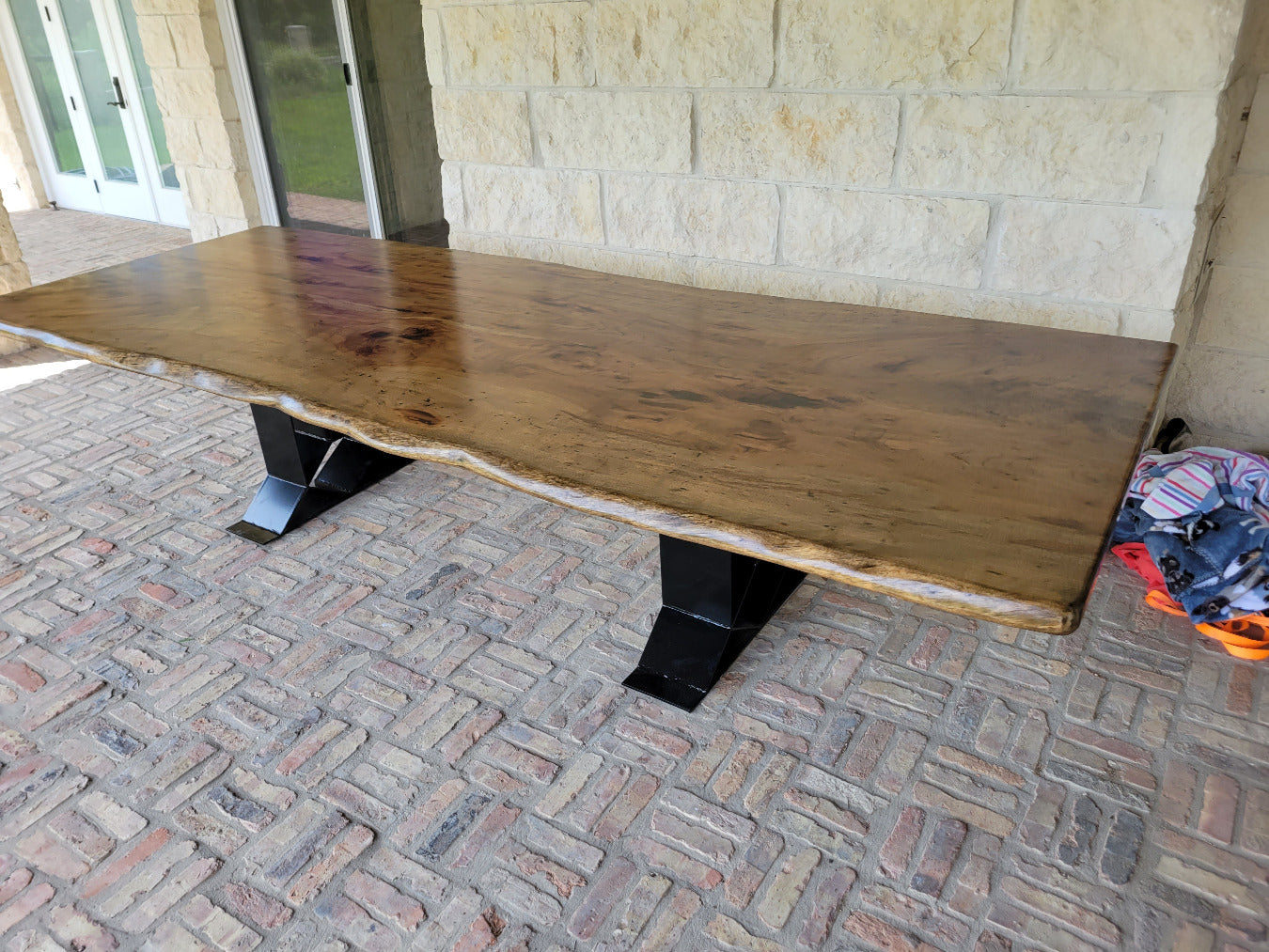 A rustic live-edge Pecan dining table with a natural wood top and black metal X-style legs,