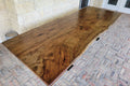 A rustic live-edge Pecan dining table with a natural wood top and black metal X-style legs,
