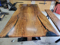 White oak dining table with a natural finish and black resin inclusions with matching bench 