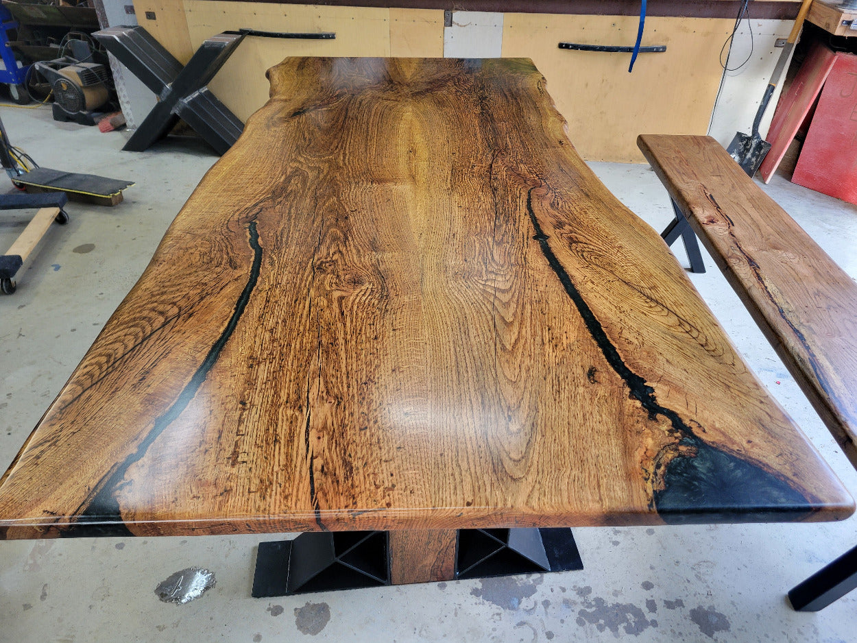 White oak dining table with a natural finish and black resin inclusions with matching bench 