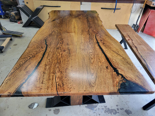 White oak dining table with a natural finish and black resin inclusions with matching bench 