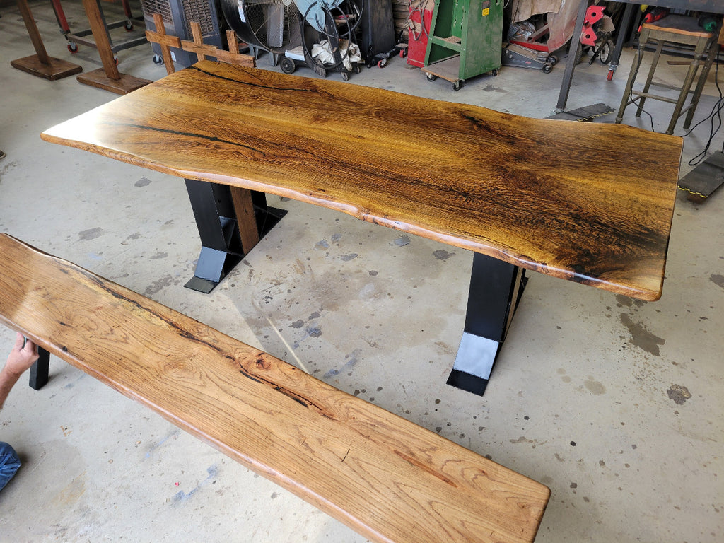 White oak dining table with a natural finish and black resin inclusions with matching bench 