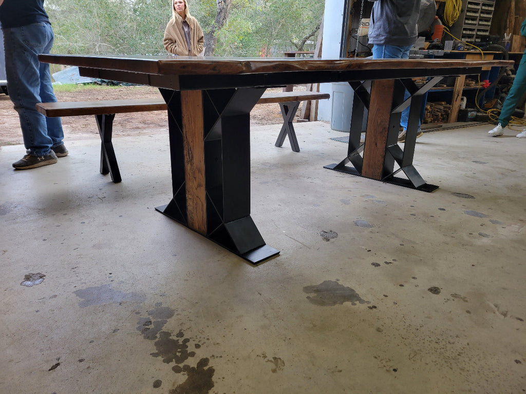 White oak dining table with a natural finish and black resin inclusions with matching bench showing geometric designed metal legs with wood inserts