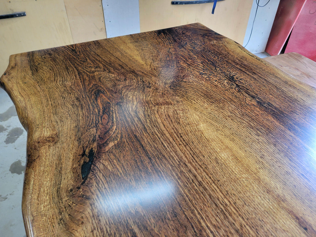 White oak dining table with a natural finish and black resin inclusions with matching bench 