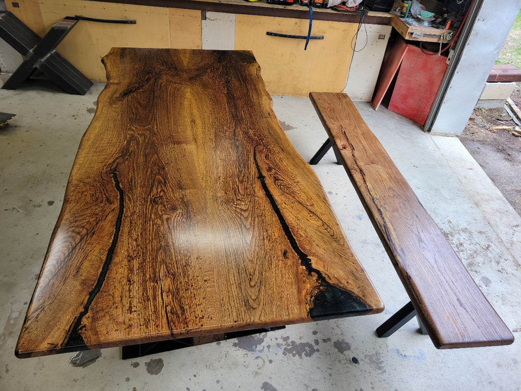 White oak dining table with a natural finish and black resin inclusions with matching bench 