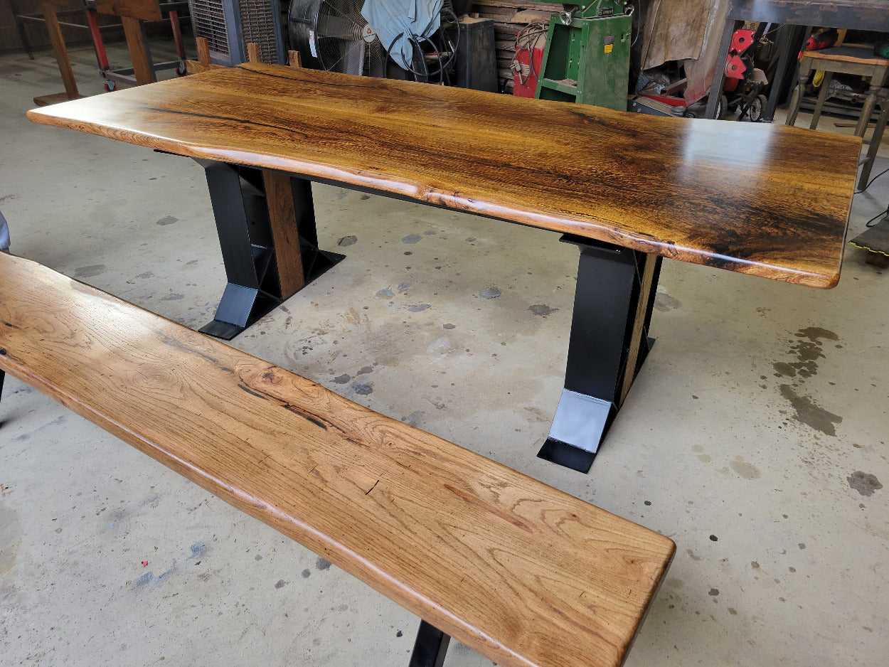 White oak dining table with a natural finish and black resin inclusions with matching bench 