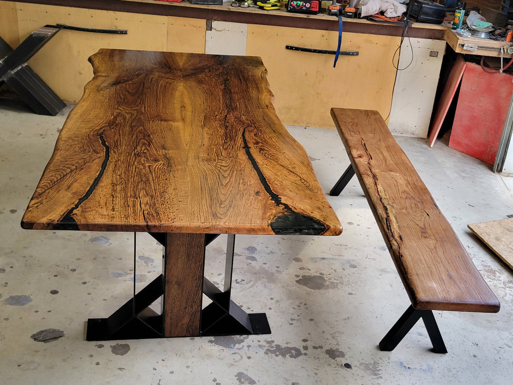 White oak dining table with a natural finish and black resin inclusions with matching bench 