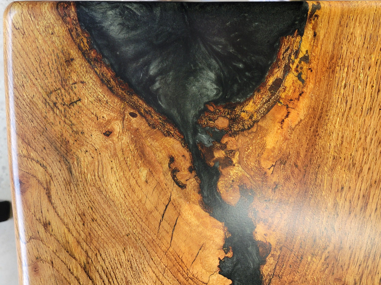 White oak dining table with a natural finish and black resin inclusions with matching bench 