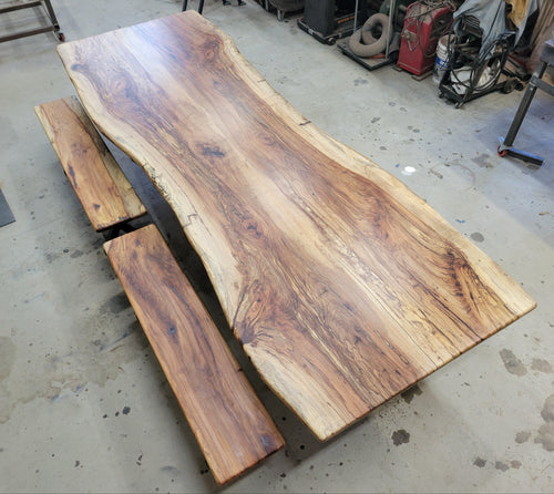 A large live-edge Pecan dining table with matching bench seats, in the natural color with x-style black metal legs