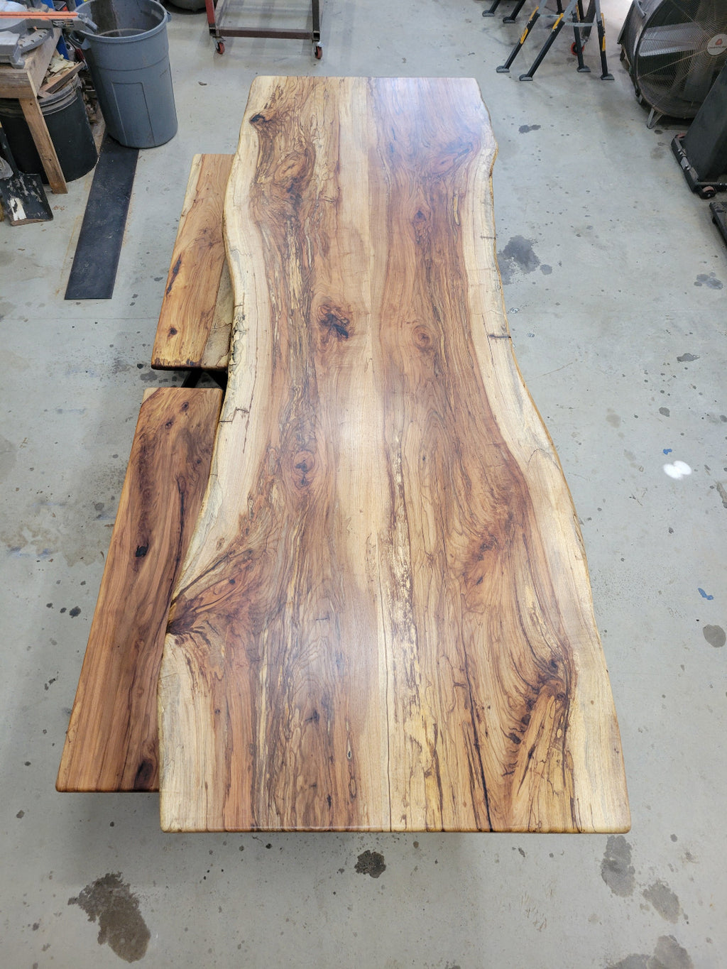 A large live-edge Pecan dining table with matching bench seats, in the natural color with x-style black metal legs