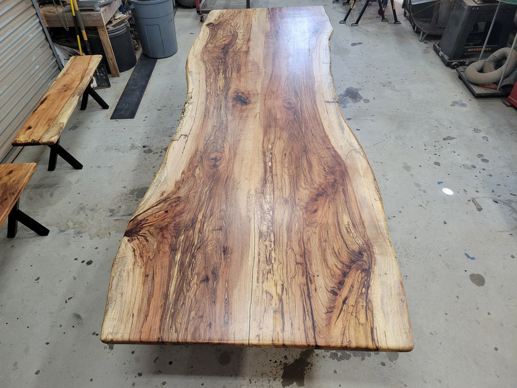 A large live-edge Pecan dining table with matching bench seats, in the natural color with x-style black metal legs