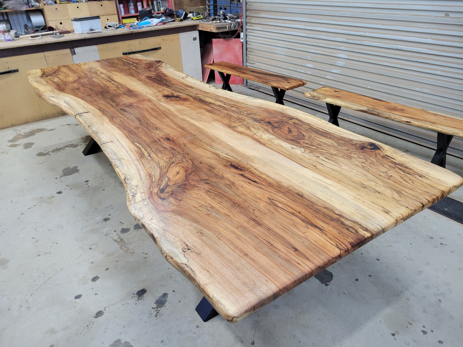 A large live-edge Pecan dining table with matching bench seats, in the natural color with x-style black metal legs