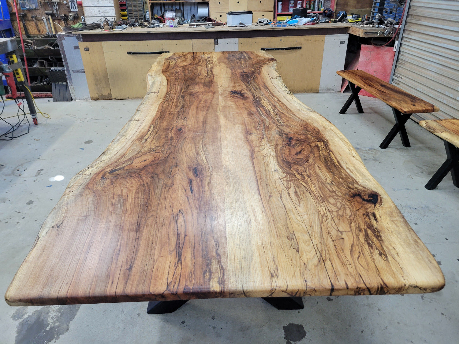 A large live-edge Pecan dining table with matching bench seats, in the natural color with x-style black metal legs
