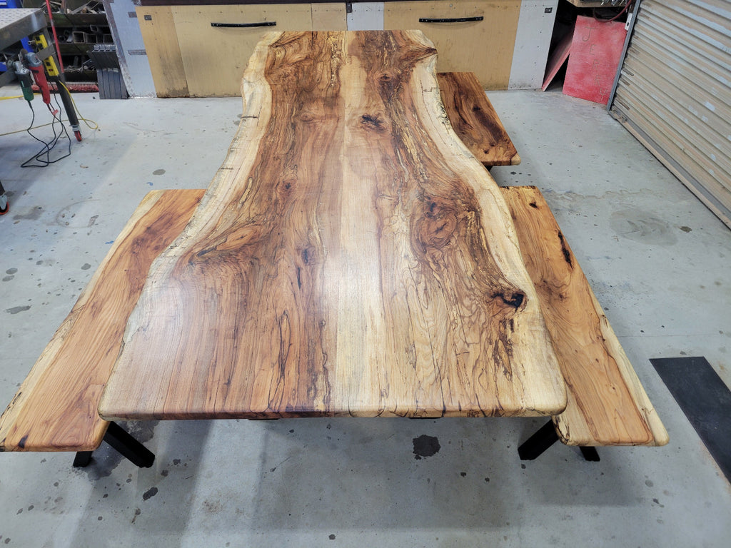 A large live-edge Pecan dining table with matching bench seats, in the natural color with x-style black metal legs