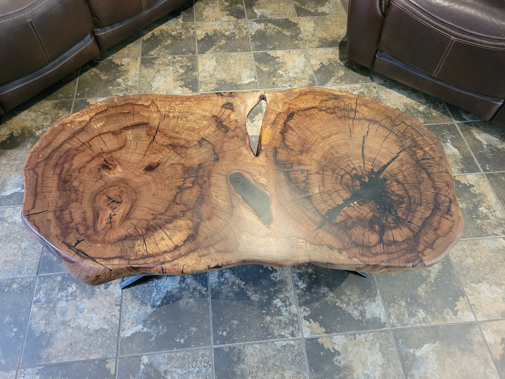 Wooden double tree coffee table with a natural, rustic design and black metal cross style legs in a living room setting.
