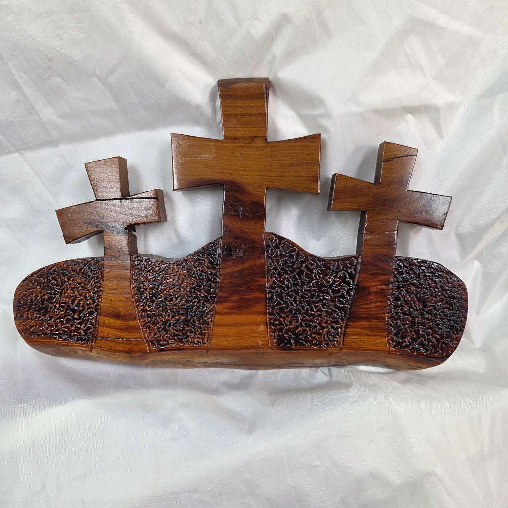 A Bois D'Arc decorative wall plaque featuring three stylized Christian crosses cut from a single slab, hand carved with burned finish sho sugi ban with natural grain 