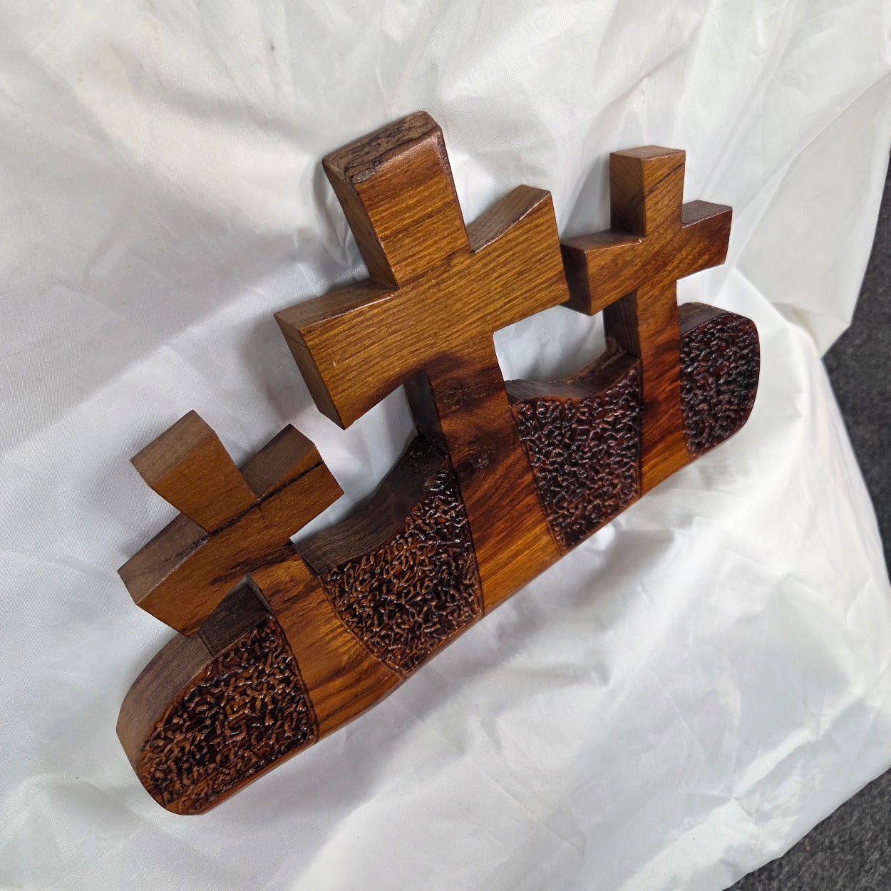 A Bois D'Arc decorative wall plaque featuring three stylized Christian crosses cut from a single slab, hand carved with burned finish sho sugi ban with natural grain 