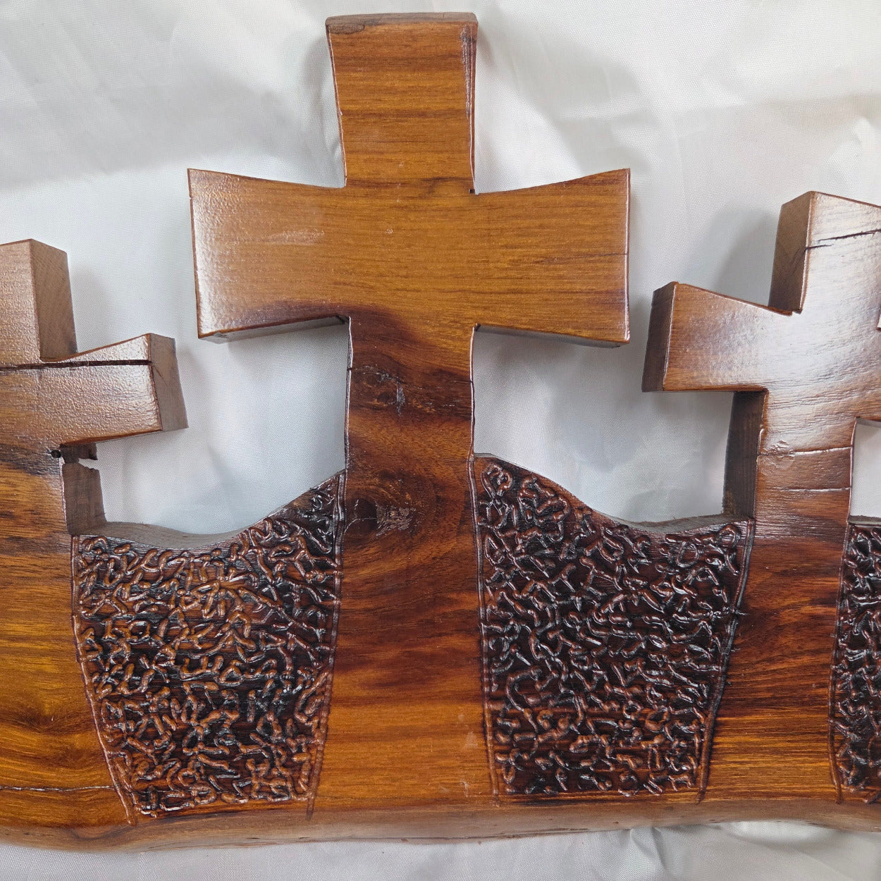 A Bois D'Arc decorative wall plaque featuring three stylized Christian crosses cut from a single slab, hand carved with burned finish sho sugi ban with natural grain 