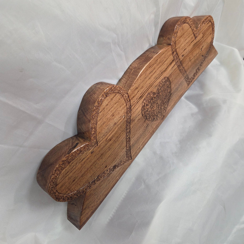A handcrafted White Oak wooden plaque featuring three stacked heart shapes with engraved details, displayed on a wrinkled white fabric background.