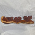 A rustic wooden decorative plaque featuring three hand carved hearts made from a single mesquite slab