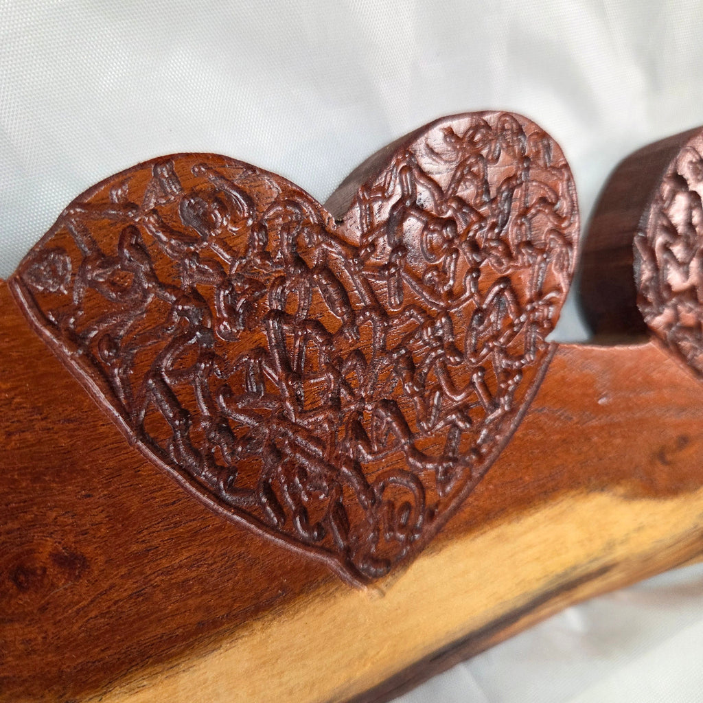 A rustic wooden decorative plaque featuring three hand carved hearts made from a single mesquite slab