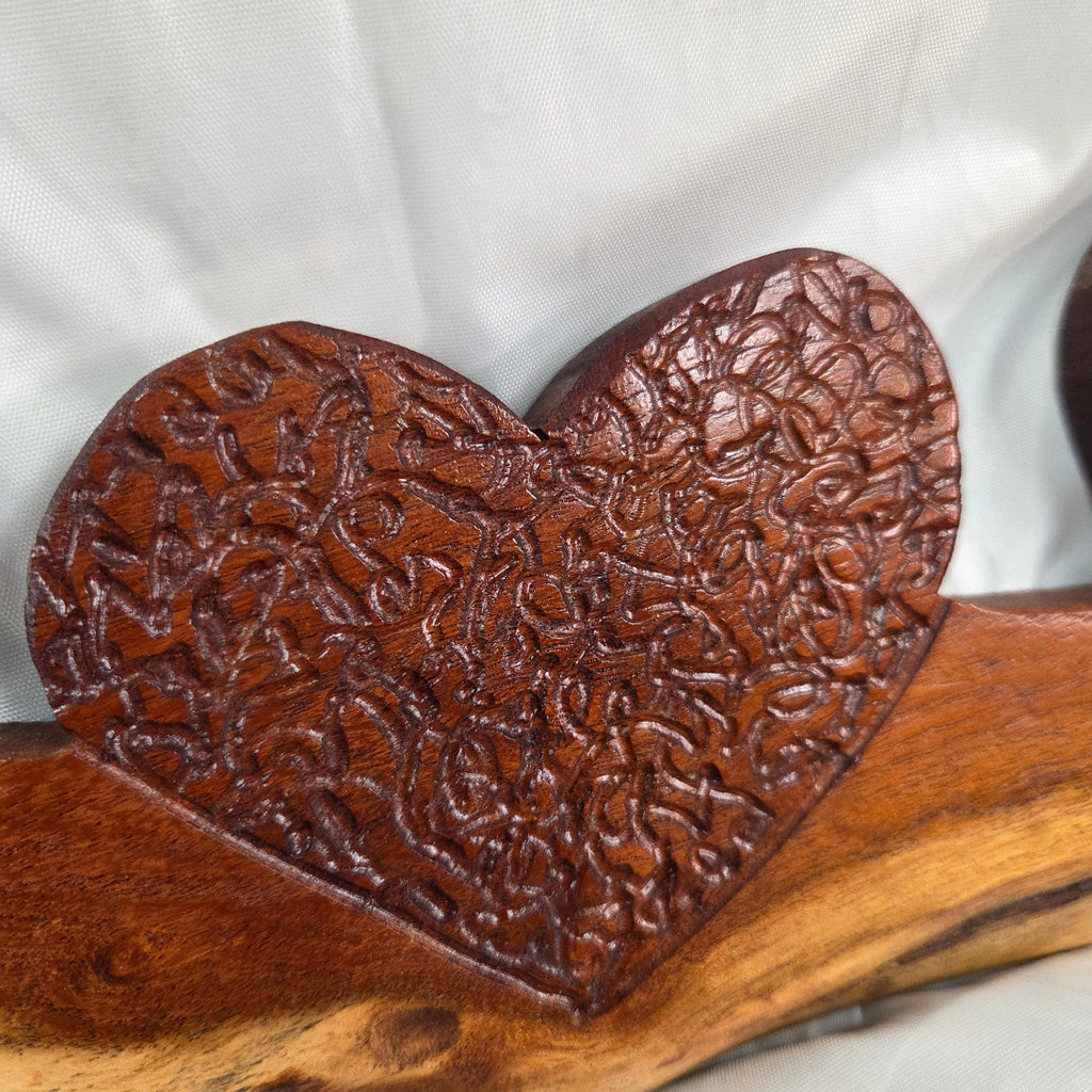 A rustic wooden decorative plaque featuring three hand carved hearts made from a single mesquite slab