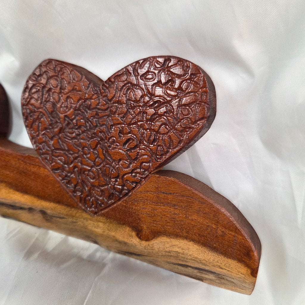 A rustic wooden decorative plaque featuring three hand carved hearts made from a single mesquite slab