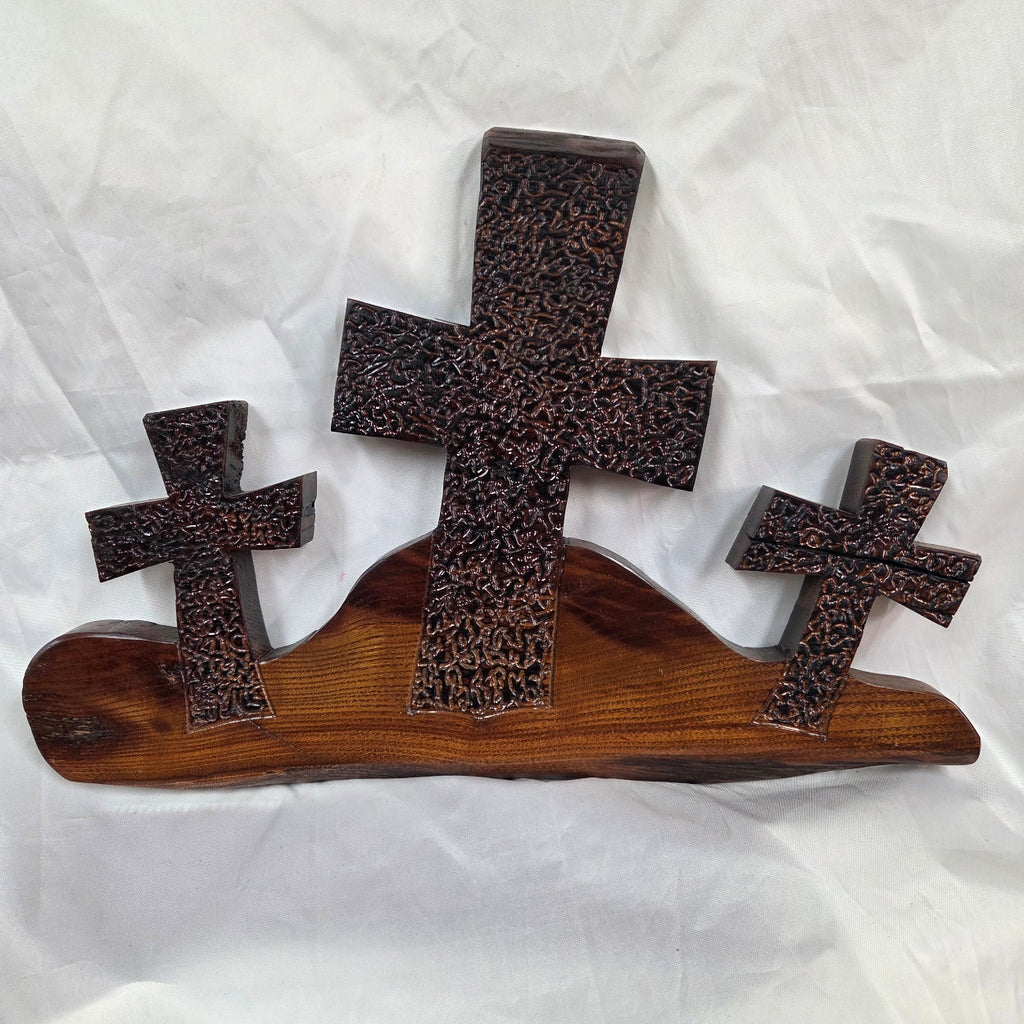 A Bois D'Arc decorative wall plaque featuring three stylized Christian crosses cut from a single slab, hand carved with burned finish sho sugi ban with natural grain 