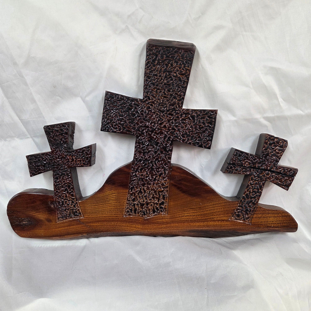 A Bois D'Arc decorative wall plaque featuring three stylized Christian crosses cut from a single slab, hand carved with burned finish sho sugi ban with natural grain 