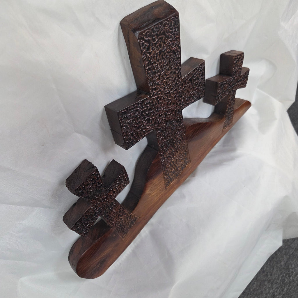A Bois D'Arc decorative wall plaque featuring three stylized Christian crosses cut from a single slab, hand carved with burned finish sho sugi ban with natural grain 