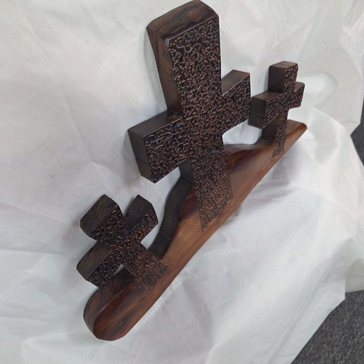 A Bois D'Arc decorative wall plaque featuring three stylized Christian crosses cut from a single slab, hand carved with burned finish sho sugi ban with natural grain 