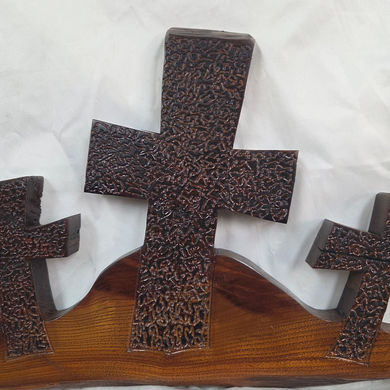 A Bois D'Arc decorative wall plaque featuring three stylized Christian crosses cut from a single slab, hand carved with burned finish sho sugi ban with natural grain 