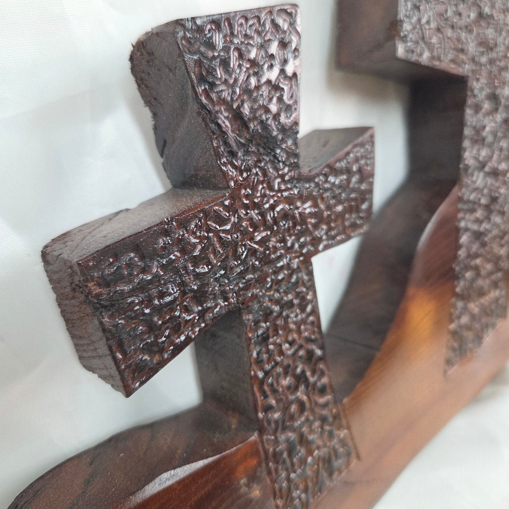A Bois D'Arc decorative wall plaque featuring three stylized Christian crosses cut from a single slab, hand carved with burned finish sho sugi ban with natural grain 