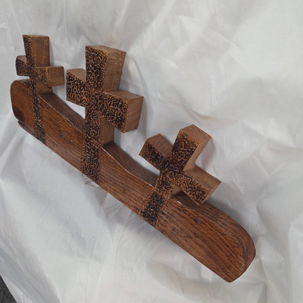 A white oak decorative wall plaque featuring three stylized Christian crosses cut from a single slab, hand carved with burned finish sho sugi ban with natural grain 