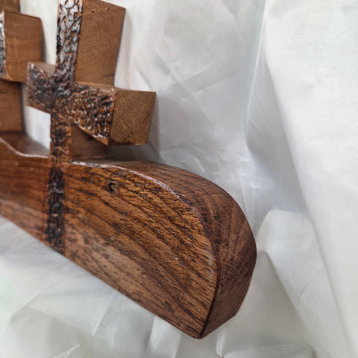 A white oak decorative wall plaque featuring three stylized Christian crosses cut from a single slab, hand carved with burned finish sho sugi ban with natural grain 