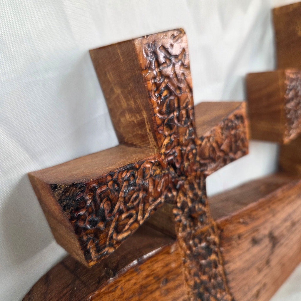 A white oak decorative wall plaque featuring three stylized Christian crosses cut from a single slab, hand carved with burned finish sho sugi ban with natural grain 