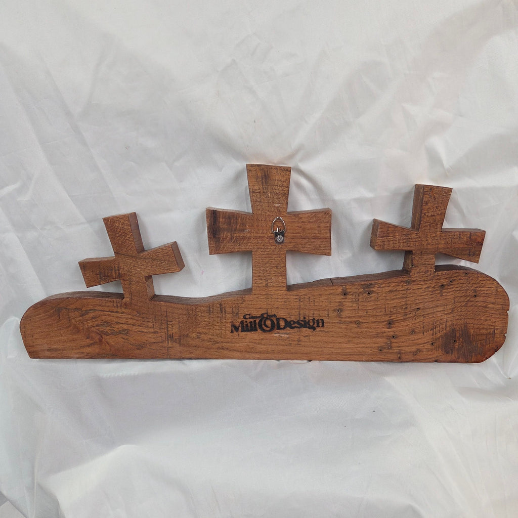 A white oak decorative wall plaque featuring three stylized Christian crosses cut from a single slab, hand carved with burned finish sho sugi ban with natural grain 