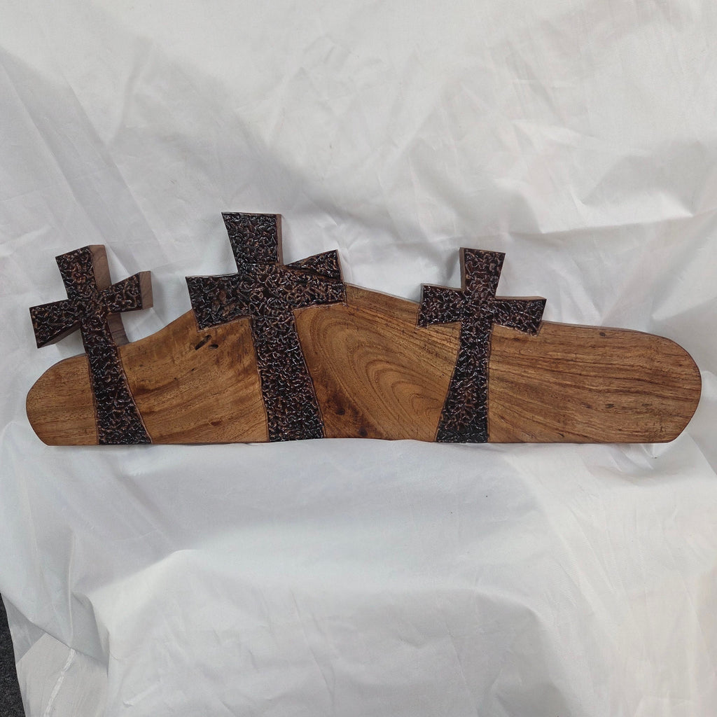 A Pecan decorative wall plaque featuring three stylized Christian crosses cut from a single slab, hand carved with burned finish sho sugi ban with natural grain 