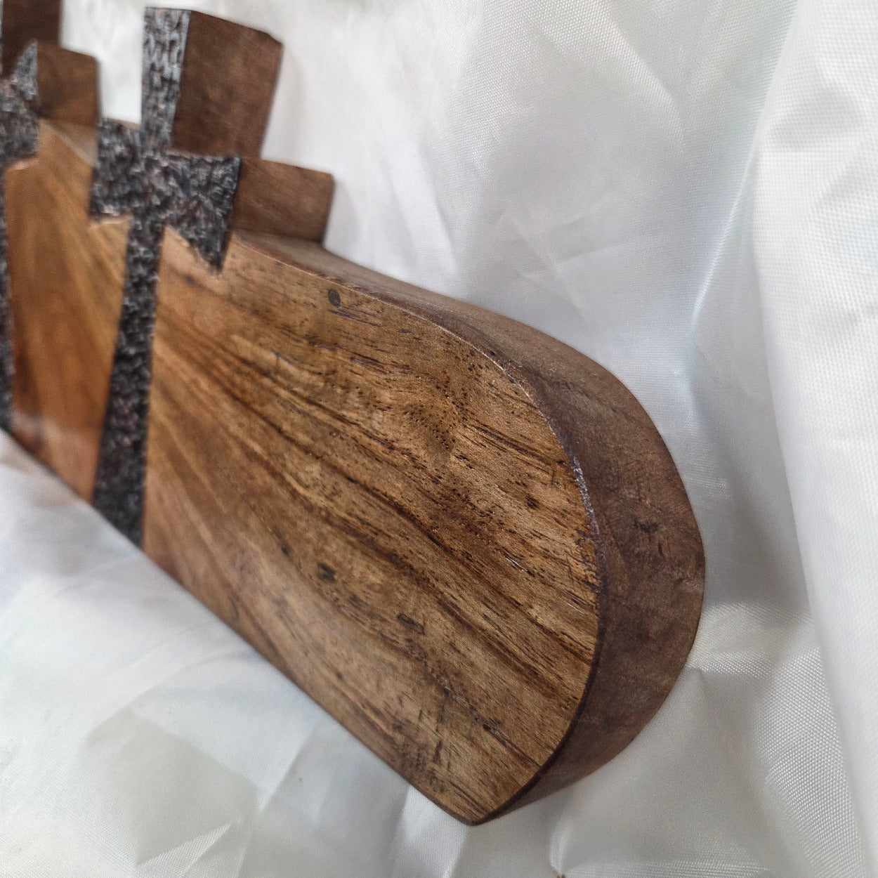 A Pecan decorative wall plaque featuring three stylized Christian crosses cut from a single slab, hand carved with burned finish sho sugi ban with natural grain 