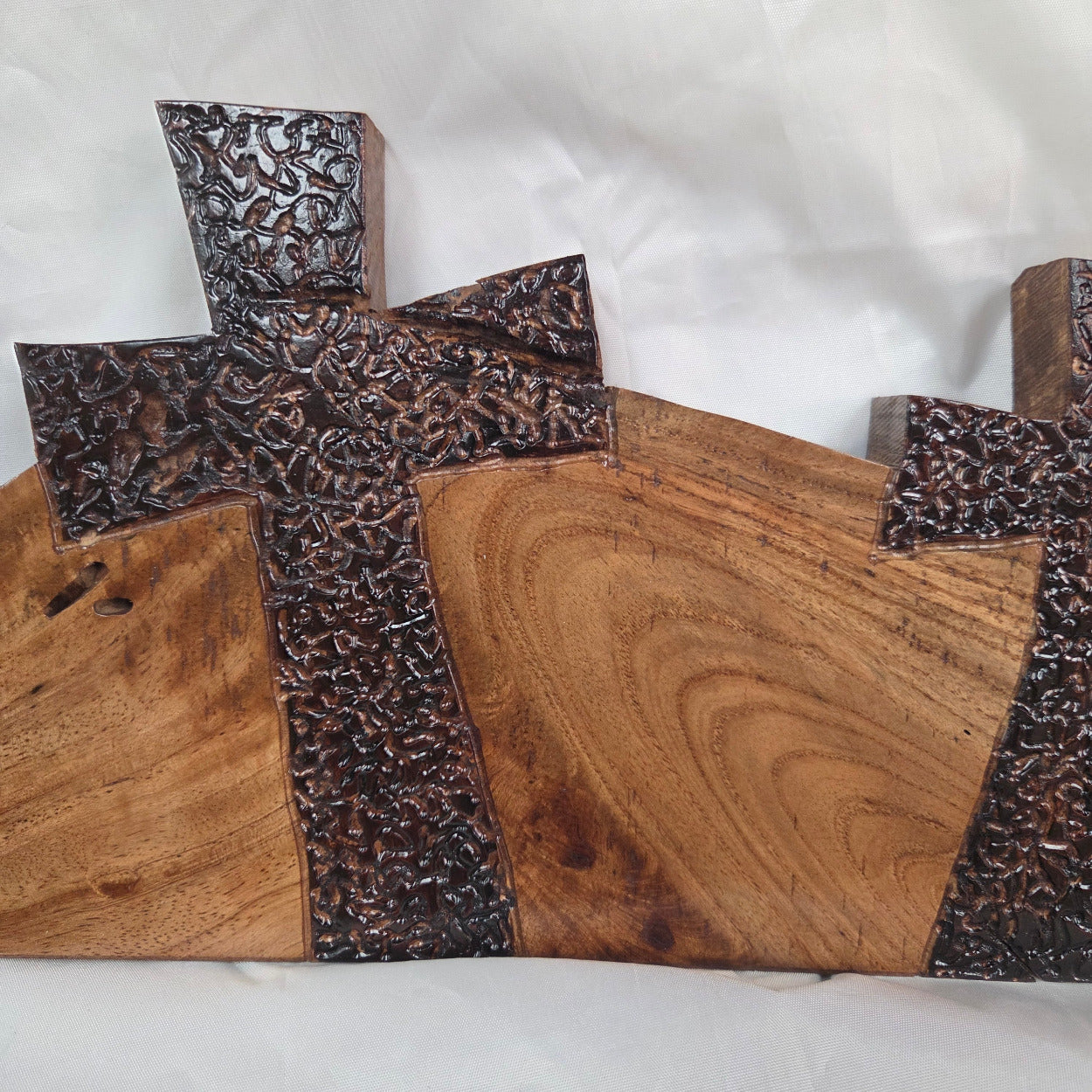 A Pecan decorative wall plaque featuring three stylized Christian crosses cut from a single slab, hand carved with burned finish sho sugi ban with natural grain 