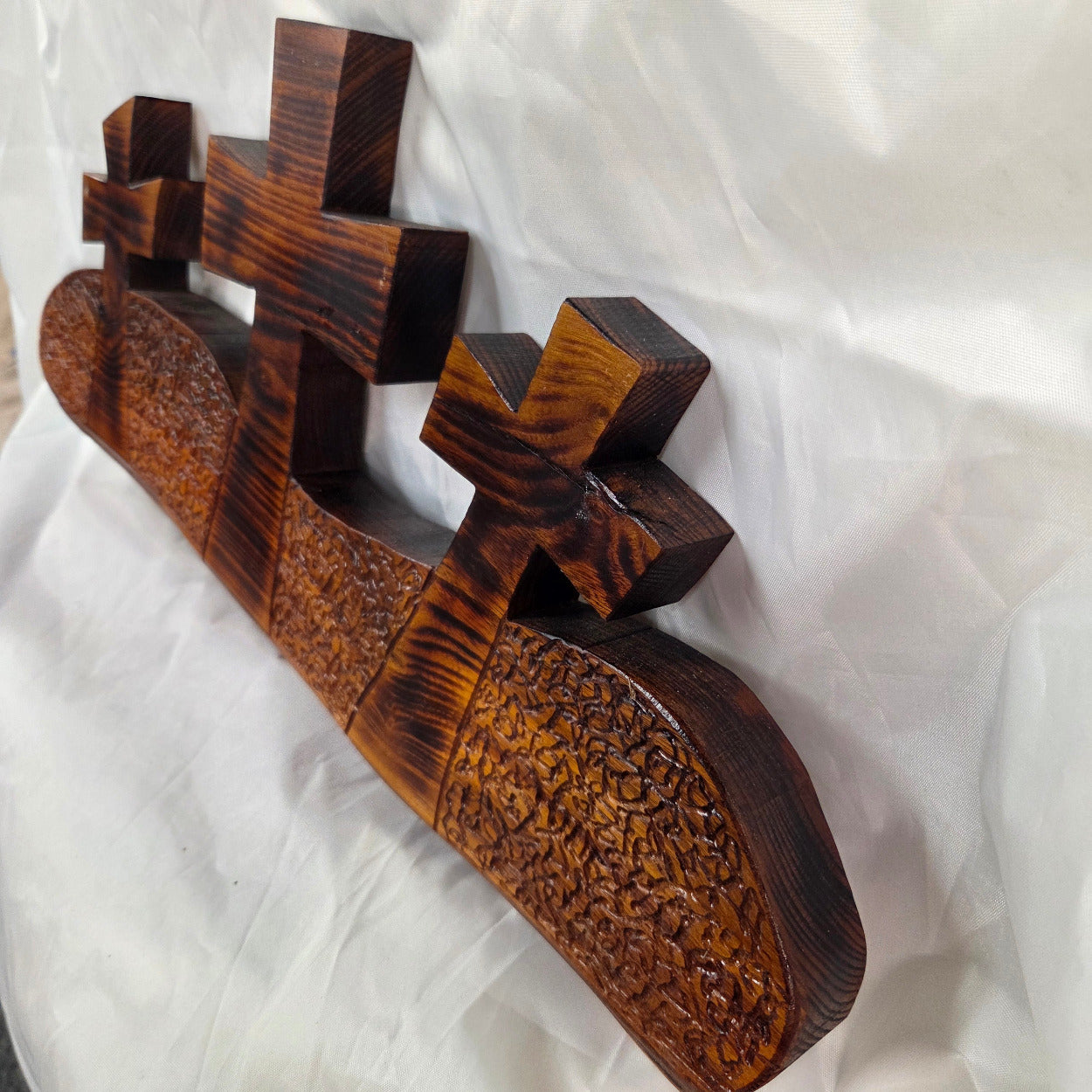 A Bois D'Arc decorative wall plaque featuring three stylized Christian crosses cut from a single slab, hand carved with burned finish sho sugi ban