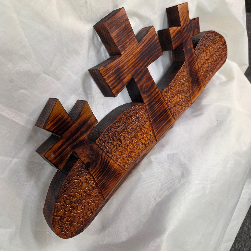 A Bois D'Arc decorative wall plaque featuring three stylized Christian crosses cut from a single slab, hand carved with burned finish sho sugi ban