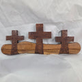 A white oak decorative wall plaque featuring three stylized Christian crosses cut from a single slab, hand carved with dark brown stained crosses and natural color base