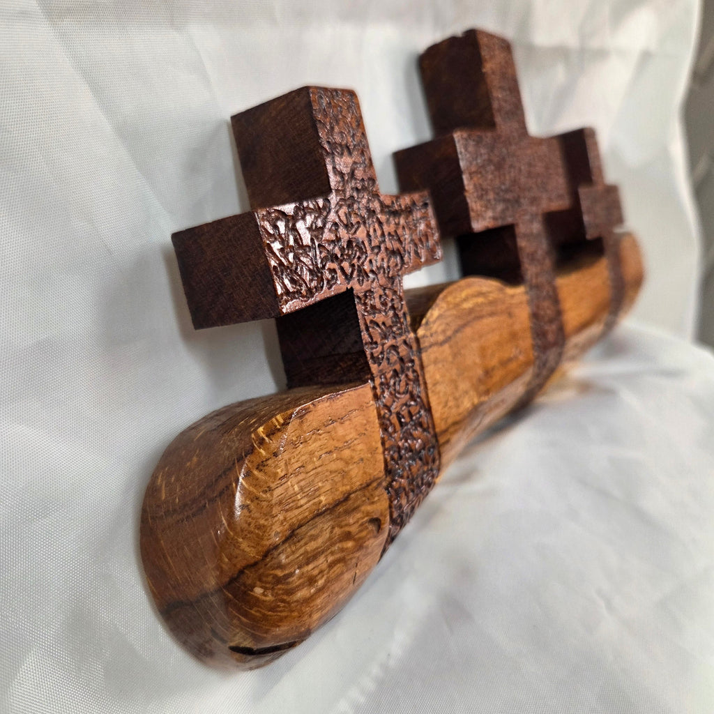 A white oak decorative wall plaque featuring three stylized Christian crosses cut from a single slab, hand carved with dark brown stained crosses and natural color base