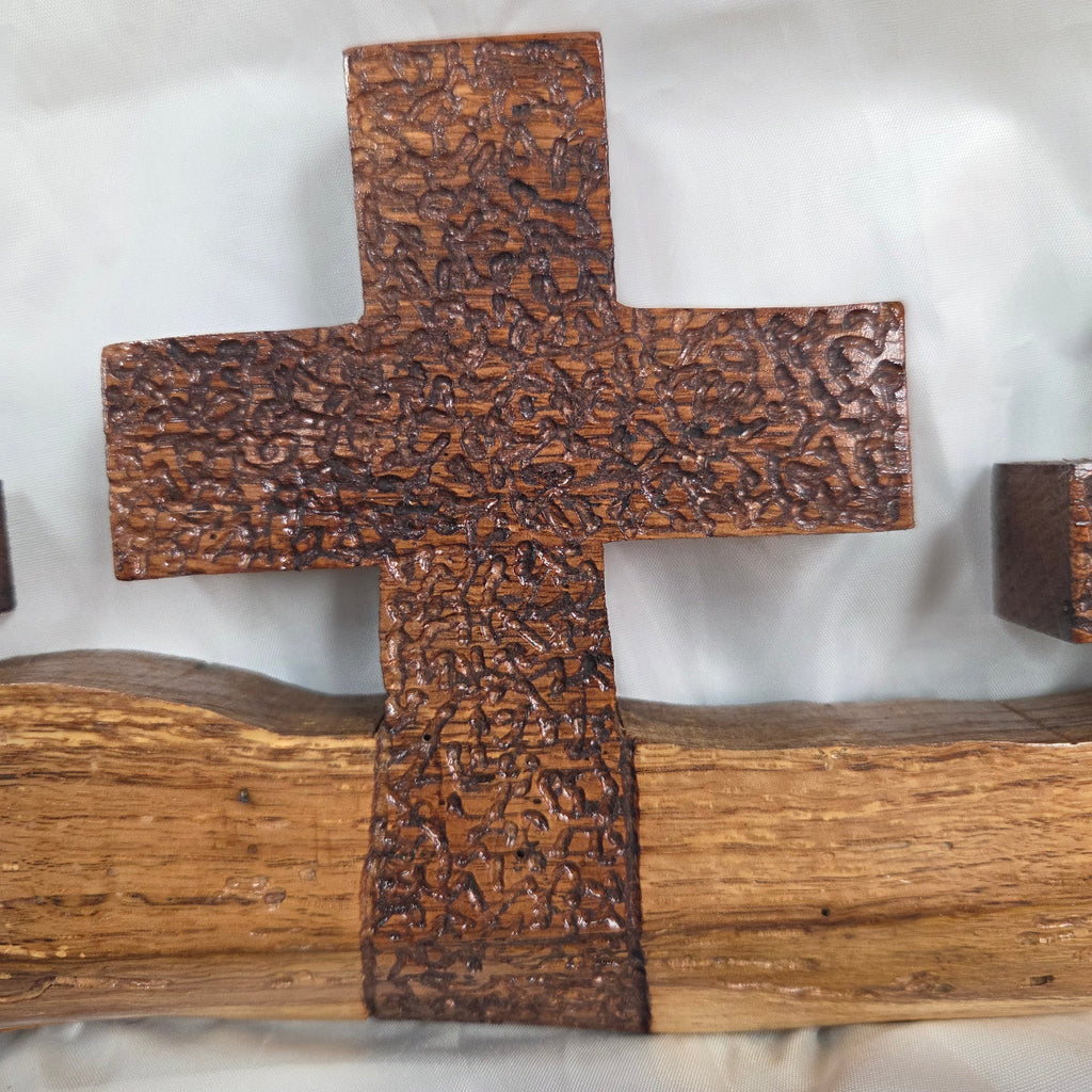 A white oak decorative wall plaque featuring three stylized Christian crosses cut from a single slab, hand carved with dark brown stained crosses and natural color base