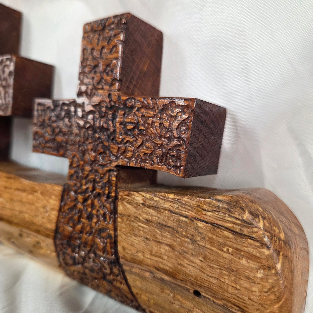 A white oak decorative wall plaque featuring three stylized Christian crosses cut from a single slab, hand carved with dark brown stained crosses and natural color base