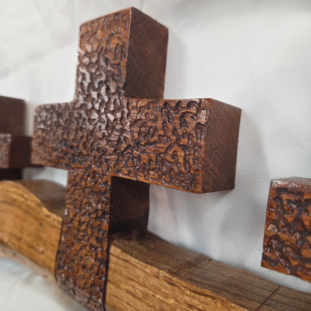 A white oak decorative wall plaque featuring three stylized Christian crosses cut from a single slab, hand carved with dark brown stained crosses and natural color base