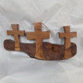 A white oak decorative wall plaque featuring three stylized Christian crosses cut from a single slab, hand carved with dark brown wooden base, 