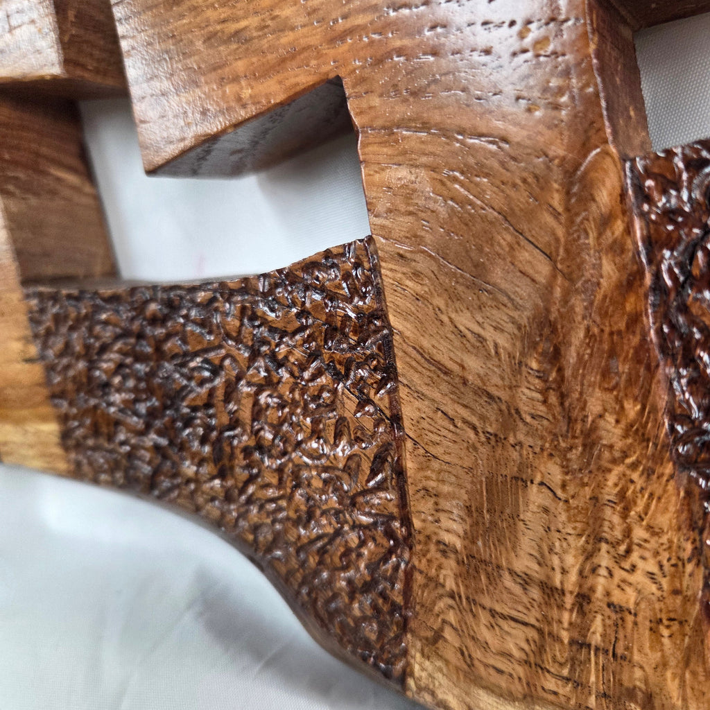 A white oak decorative wall plaque featuring three stylized Christian crosses cut from a single slab, hand carved with dark brown wooden base, 